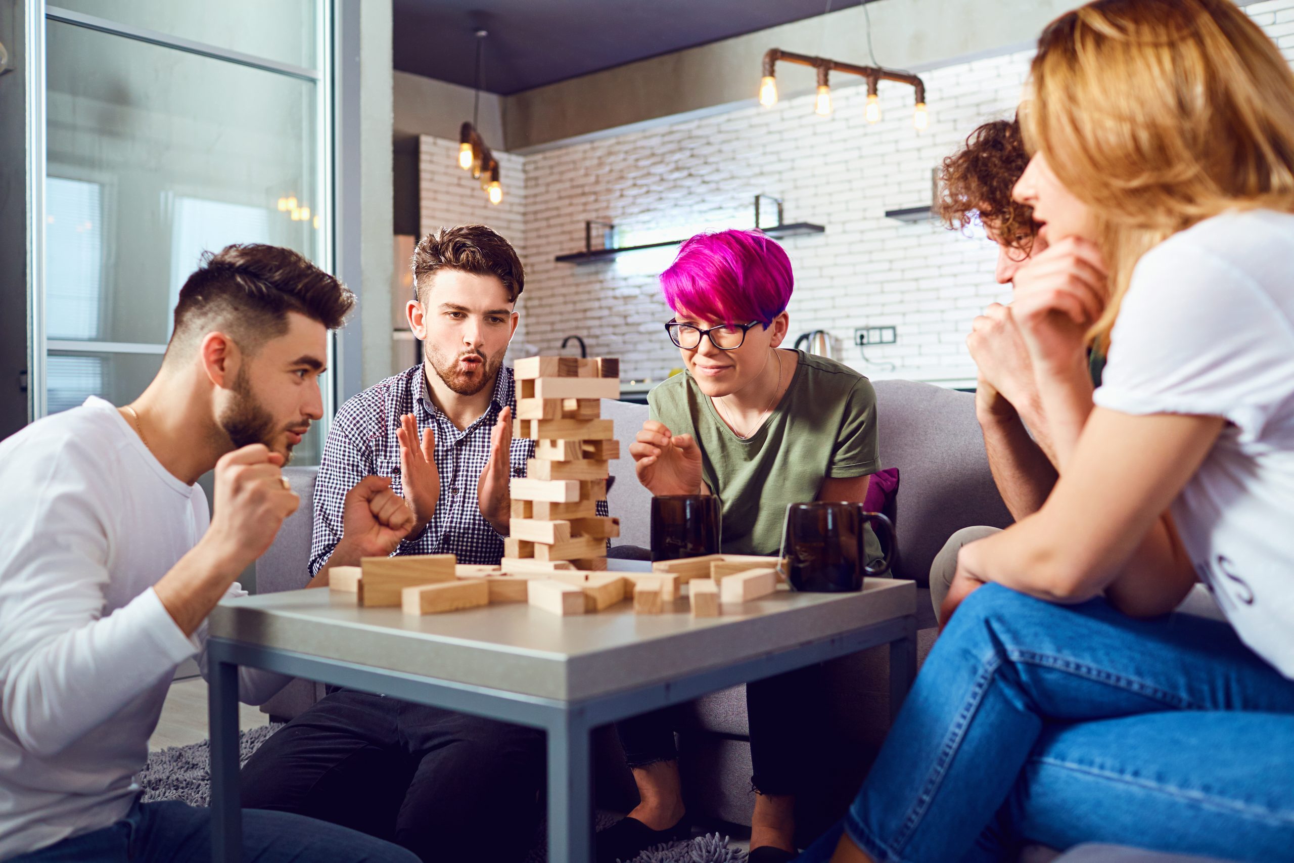 A cheerful group of friends play board games. Retaining talent. Image: Group of young people playing jenga