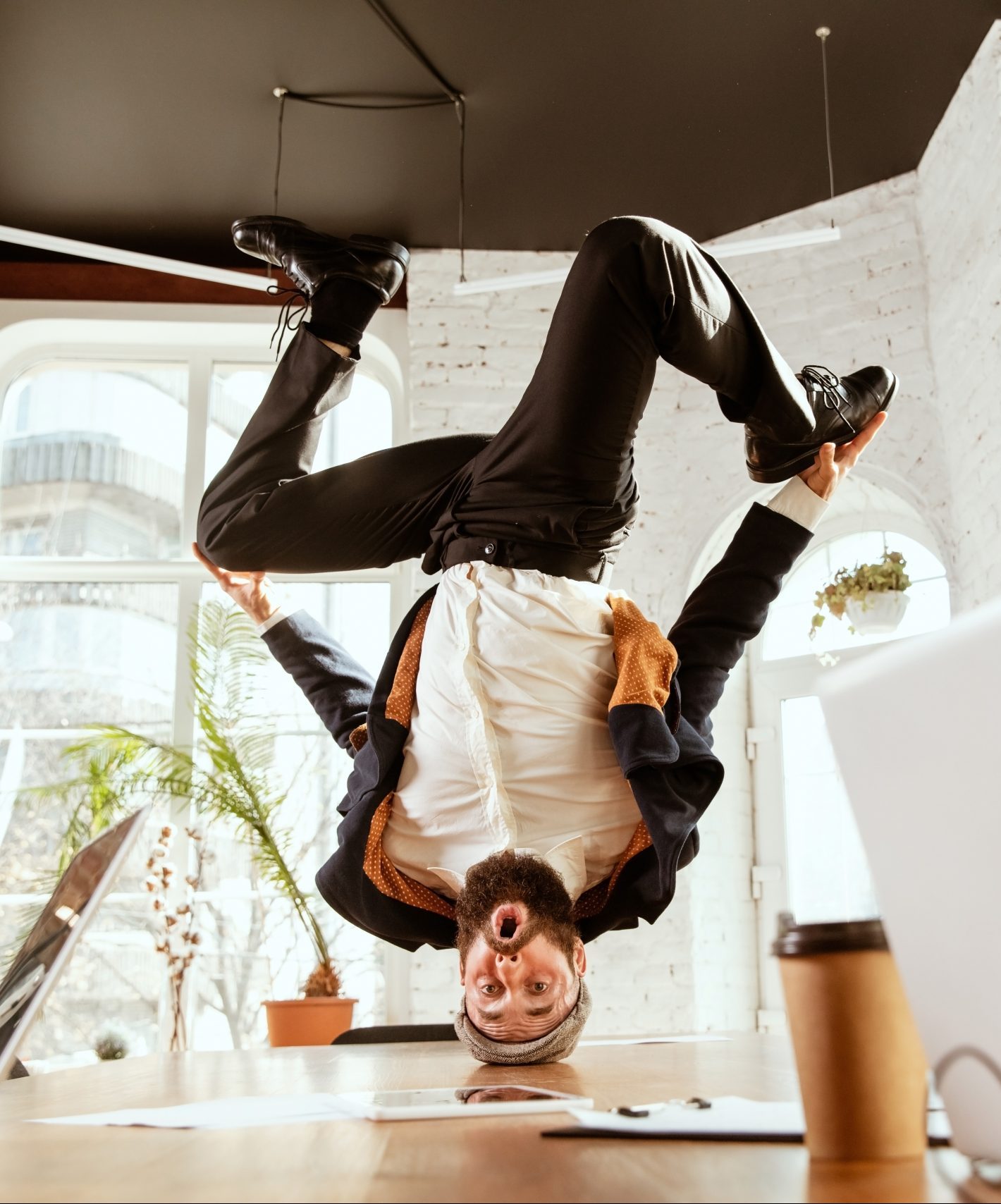 Businessman having fun dancing break dance in the office at work Keeping your best talent. Image: Businessman doing a headstand over a meeting table